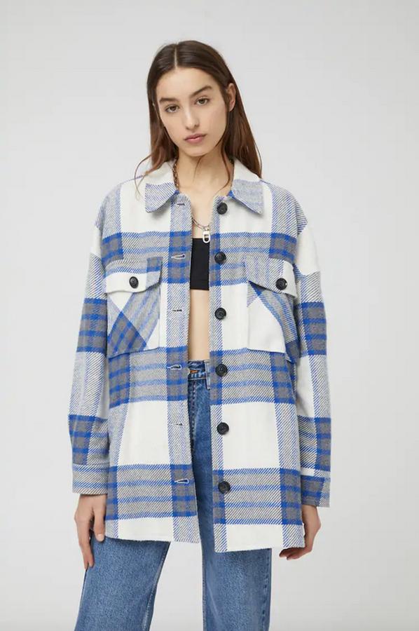 Con cuello clásico, bolsillos delanteros con solapa y botón y cierre frontal a contraste, esta sobrecamisa de Pull&Bear con cuadros azules y grises sobre fondo blanco está disponible entre las tallas XS y XL por 29,99 euros.