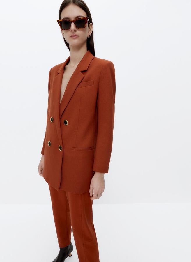 Diseño oversize cruzado con cierre de botones a contraste en negro para esta blazer en naranja teja que tiene un precio de 159 euros y está disponible entre las tallas XS y L.