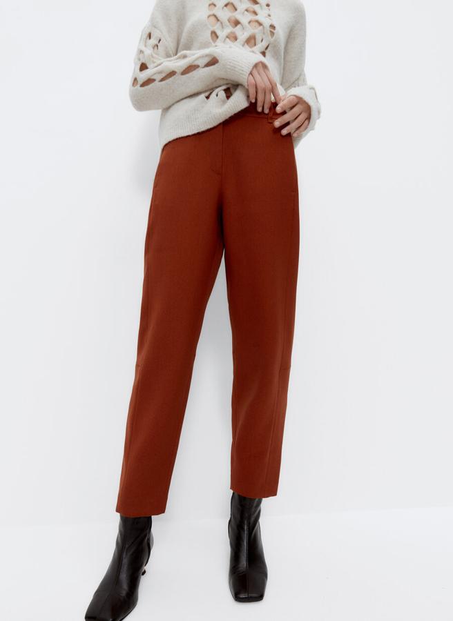 A juego con la blazer, en naranja teja, con detalle de costuras vistas, bolsillos laterales y cierre de cremallera y gancho metálico, este pantalón tiene un precio de 79 euros y está disponible entre las tallas XS y L.