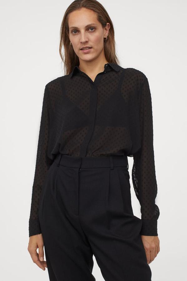 En tejido fluido con cuello estrecho, botones ocultos por tapeta en el frontal y bajo redondeado, esta blusa negra de H&M confeccionada con poliéster parcialmente reciclado tiene un precio de 19,99 euros y podemos encontrarla entre las tallas XS y XXL.
