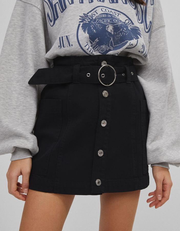 En color negro, con cierre frontal de botones metalizados y cinturón extraíble a tono, esta falda cargo de Bershka ha pasado de 17,99 euros a 10,79 euros y podemos encontrarla en las tallas 32, 34 y 40.