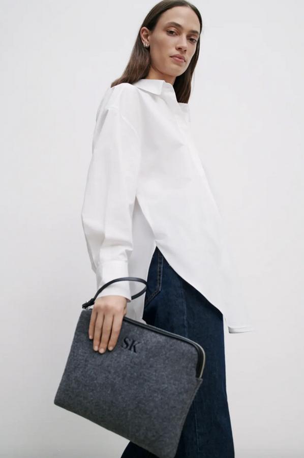 En color gris y confeccionado en fieltro, este bolso formato sobre de Zara se adapta a nuestras tablets y portátiles y tiene cierre mediante cremallera con tirador. Cuesta 9,95 euros y por un euro más se puede personalizar.