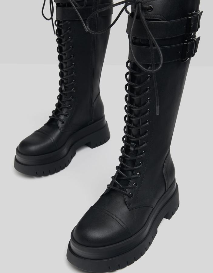 Con un tacón de seis centímetros de altura, estas botas con plataforma en color negro cuentan con cierre mediante cremallera y plataforma track. Con detalle de tiras con hebillas y cordones, tienen un precio de 55,99 euros.