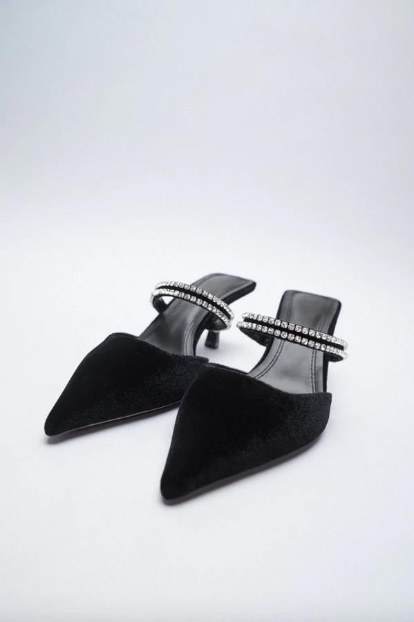 Diseño mule en color negro para estos zapatos de Zara con corte de terciopelo con tiras de brillos en el empeine. Con tacón fino y acabado en punta, podemos encontrarlos entre los números 35 y 42 por 29,95 euros.