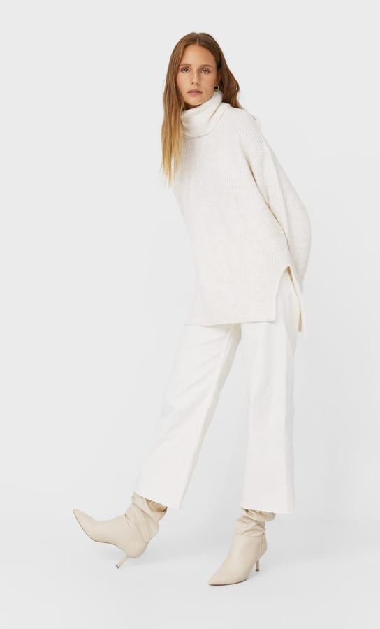 Con cuello cisne, manga larga y bajos rectos asimétricos con aberturas laterales, este jersey de Stradivarius que está disponible en gris, blanco y negro tiene un precio de 25,99 euros y está disponible entre las tallas XS y L.