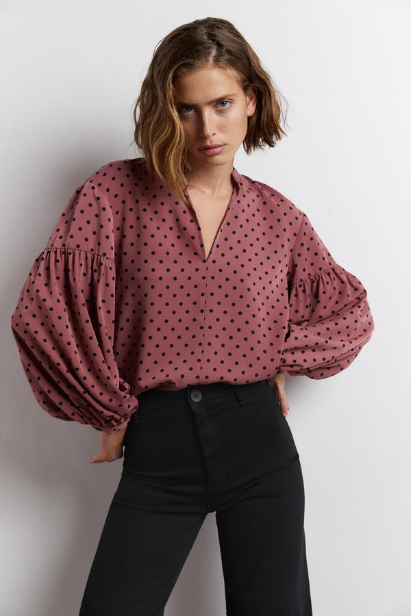 Este blusón de hombros caídos, mangas amplias acabadas en puño fino y escote de pico es de Sfera y viene en un bonito rosa colorete con estampado de lunares a contraste en negro. Cuesta 29,99 euros y está disponible en las tallas S, M y L.