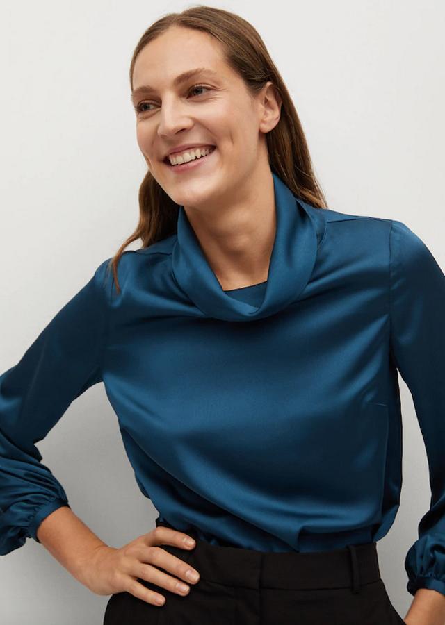 Disponible en azul petróleo y en crudo, esta blusa satinada de Mango de diseño recto y mangas largas viene con cuello amplio alto. Cuesta 39,99 euros y está disponible entre las tallas S y XL.