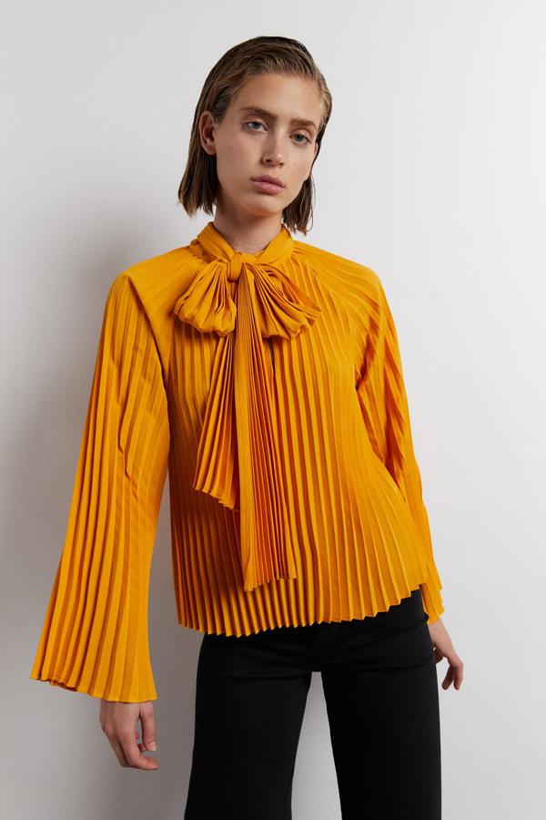 En color huevo, con diseño plisado, cierre de botón en el escote y lazada también plisada en el cuello, esta bonita y original blusa de Sfera cuesta 29,99 euros y está disponible en las tallas S, M y L.