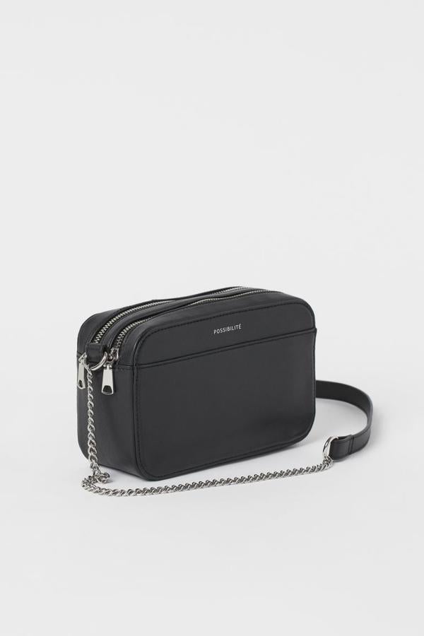 En color negro, con dos cierres superiores de cremallera y cadena de metal y correa a tono, este minibolso bandolera de H&M cuesta 14,99 euros.