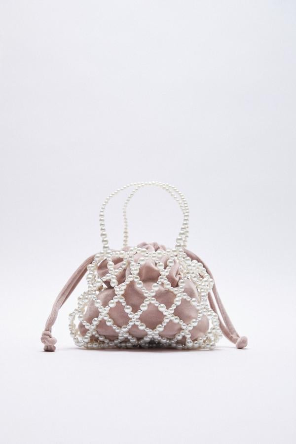 Bolso de fiesta en rosa empolvado cubierto por una red de perlas blancas de Zara (29,99 euros) Un accesorio perfecto para rematar un look navideño