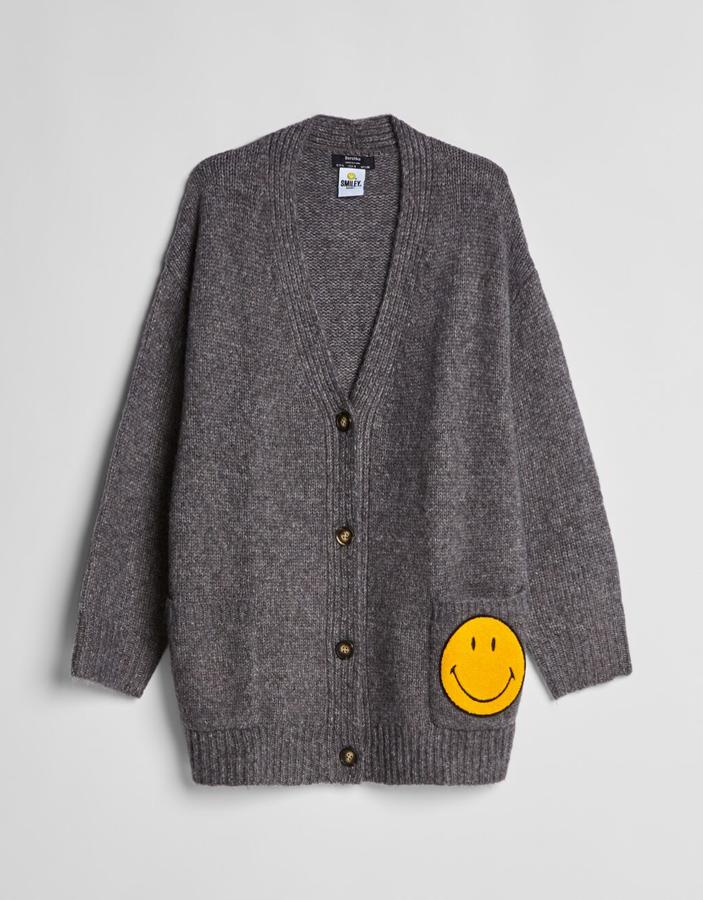 Chaqueta de punto gris con smiley en amarillo, de Bershka (29,99 euros).