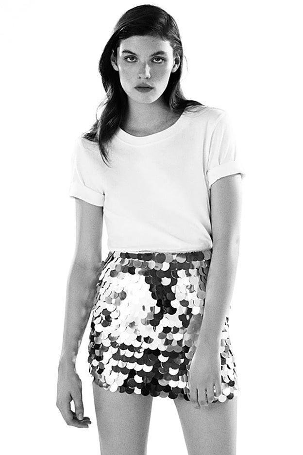 Zara propone un look con falda mini de lentejuelas con camisate blanca.