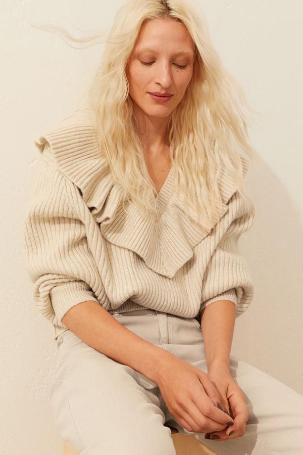 Confeccionado en punto de canalé suave con lana en la trama, este jersey beige de H&M es de diseño cropped, con escote de pico ribeteado con volante amplio y mangas largas amplias con puños ceñidos. Cuesta 39,99 euros y si a ti también te ha gustado tendrás que buscarlo en las tiendas porque en la web se ha agotado.