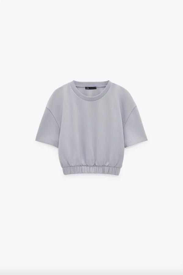 Confeccionada con al menos un 75% de algodón orgánico, esta sudadera crop en color gris es de Zara y viene con cuello redondo, manga corta y bajo acabado en elástico. También está disponible en negro y en crudo, en las tallas S, M y L por 9,95 euros.