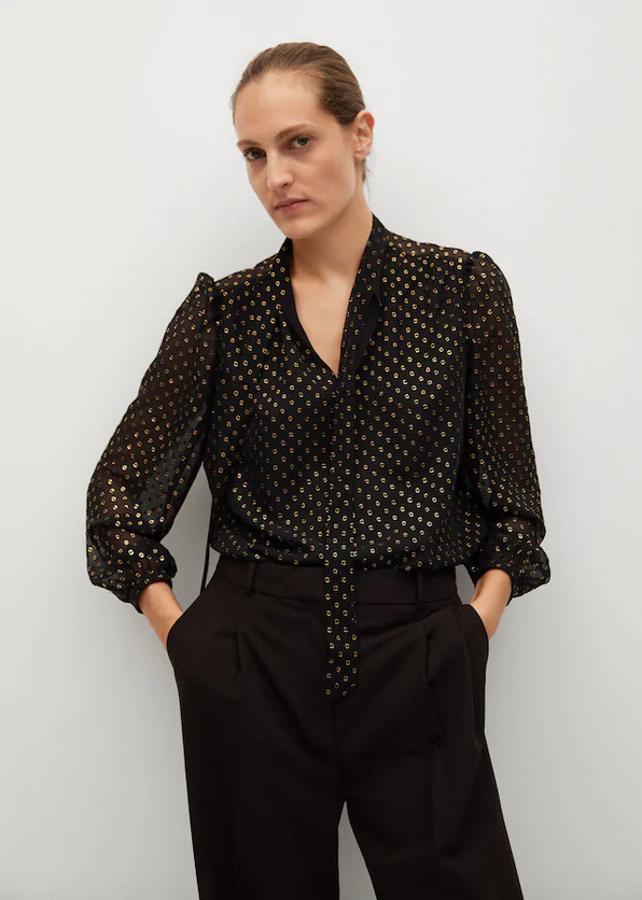 Estampado metalizado en tonos dorados para esta blusa negra de Mango en tejido semitransparente, con escote de pico con tiras al cuello y mangas largas con puños abotonados. Podemos encontrarla entre las tallas S y XL por 39,99 euros.