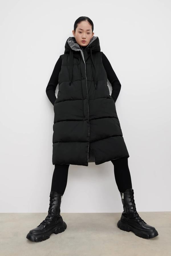 Este chaleco acolchado reversible, en color negro y gris, cuenta con cuello subido y capucha ajustable con cordón. Con cierre frontal de cremallera oculta, tiene un precio de 39,95 euros.