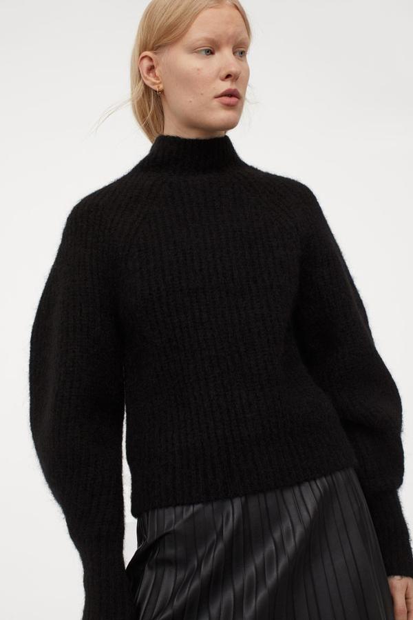 En punto de canalé suave de mezcla de lana y alpaca, este jersey con cuello perkins y mangas amplias ceñidas en los puños viene con remate de canalé en puños y bajo y está confeccionado con poliéster reciclado. Tiene un precio de 49,99 euros y está disponible entre las tallas XS y XL.