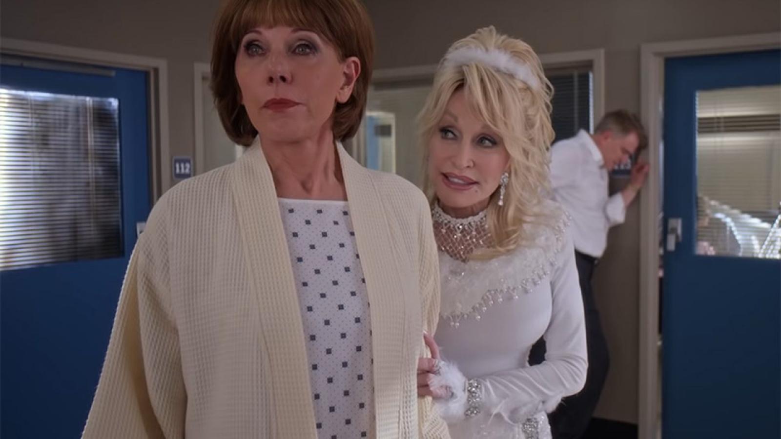 Christine Baranski al más puro señor Scrooge de Cuento de Navidad y  Dolly Parton  como un ángel con un outfit espectacular. La primera, una rica urbanita que quiere vender un pintoresco pueblo lleno de buenas personas. La segunda, el espíritu pizpireto que le recuerda lo verdaderamente importante. Navidad en la plaza es la película feel good que necesitas en cualquier sobremesa navideña