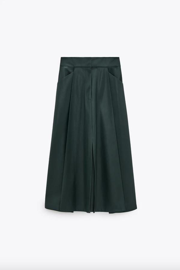 Esta falda en efecto piel color verde botella y diseño midi es de Zara y viene con bajo acabado en evasé, bolsillos laterales y cierre frontal con cremallera y botón interior. Podemos encontrarla entre las tallas XS y XL por 25,95 euros.
