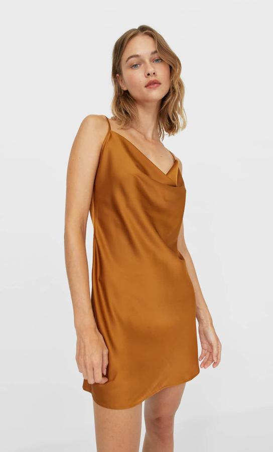 Con escote fluido y tirantes finos, este vestido corto confeccionado en satén es de Stradivarius y podemos encontrarlo en cuatro colores diferentes, gris perla, caqui, negro y camel claro entre las tallas XS y XL por 17,99 euros.