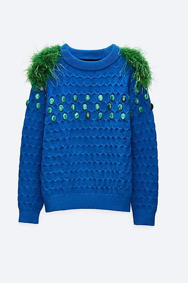 La pedrería en el frontal y las plumas verdes en los hombros, hacen de este jersey una prenda protagonista.