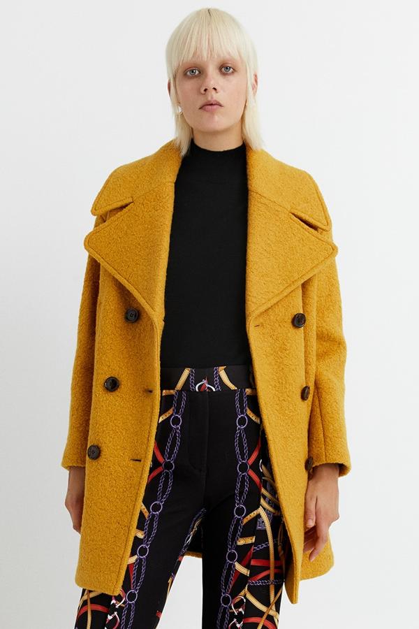 En color mostaza, este abrigo de lana con solapas grandes y cierre mediante doble botonadura frontal tiene un precio rebajado de 48,95 euros.