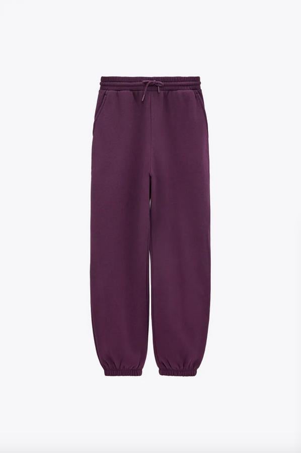 Tiro alto, cintura elástica con cordón y bajos acabados en puño para este pantalón morado de Zara con bolsillos delanteros que está confeccionado con al menos un 50% de algodón orgánico. De 17,95 euros ha pasado a costar 9,99 euros.