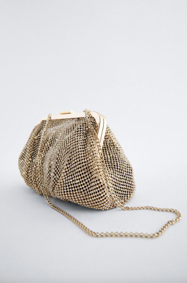En color dorado, con el cuerpo con brillos y boquilla superior metalizada, esta bandolera con asa de hombro con cadena e interior forrado con bolsillos es de Zara y de 29,95 euros ha pasado a costar 19,99 euros.