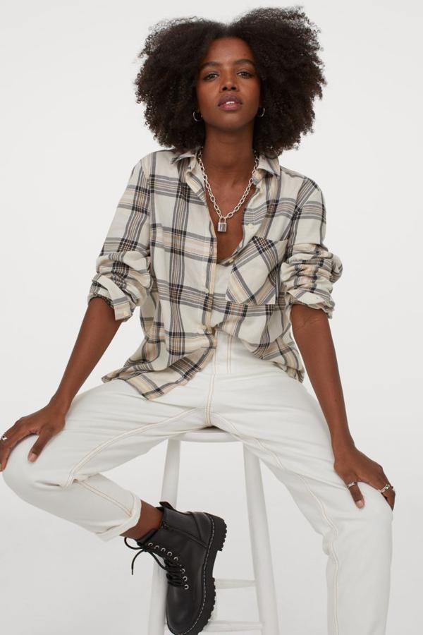 De corte recto en tejido de algodón, con cuello, tapeta de botones y bolsillo superior abierto, esta camisa beige con estampado de cuadros negros viene con canesú con pliegue de caja en la espalda, bajo redondeado y asimétrico. Tiene un precio de 14,99 euros y está disponible en las tallas XXS, XS y S.