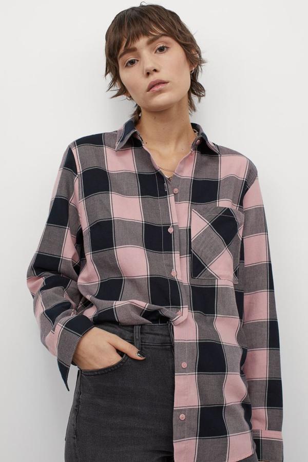De venta exclusiva en la web de H&M, esta camisa de corte recto en tejido de algodón en rosa pastel con estampado de cuadros negros viene con un bolsillo abierto en la pechera, bajo redondeado asimétrico y canesú con pliegue de caja en la espalda. Cuesta 14,99 euros y la podemos encontrar entre las tallas XXS y XL.