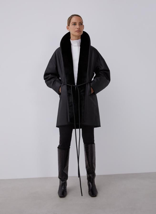 Abrigo negro de ecopiel con cinturón y solapas de pelo (rebajado de 320 a 99 euros).