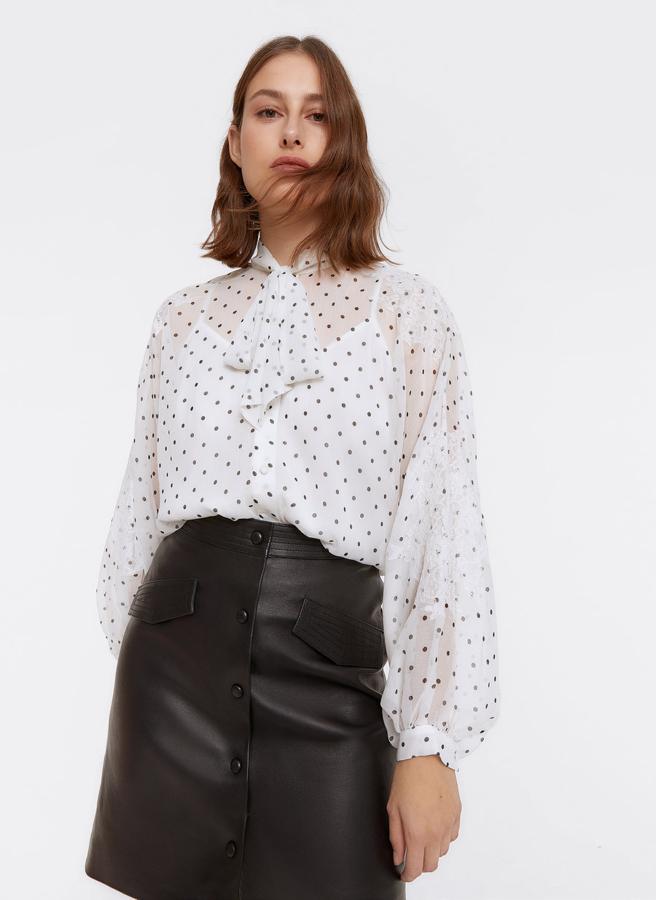 Con estampado de topos negros sobre fondo blanco, esta camisa confeccionada en un tejido de bambula viene con detalles de blondas en las mangas y en el bajo, cierre frontal de botones de nácar ocultos por tapeta y lazo al cuello. De 89 euros ha pasado a costar 59,95 euros y está disponible en las tallas S y M.