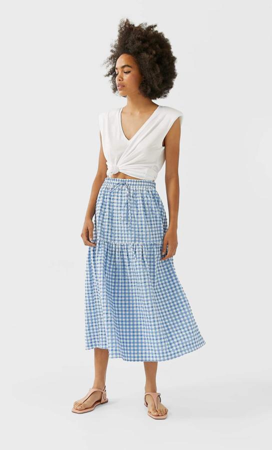 Falda midi con estampado de cuadros en blanco y azul de las rebajas de Stradivarius (12,99 euros).