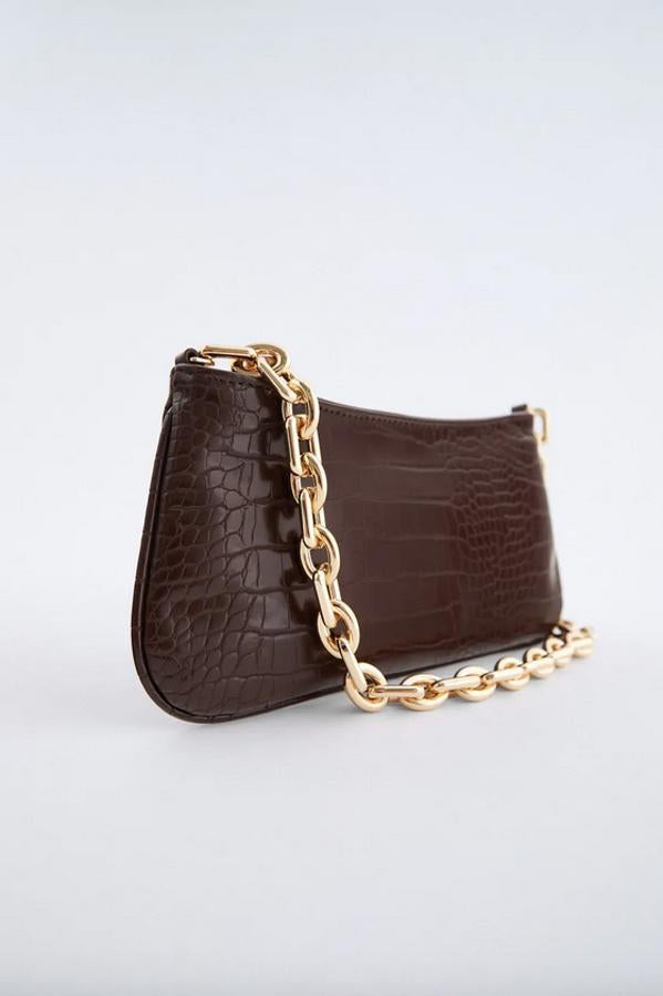 Con estampado animal en el cuerpo, asa de hombro de cadena gruesa en dorado y cierre mediante cremallera, este bolso de Zara está rebajado y de 25,95 euros ha pasado a 12,99 euros.