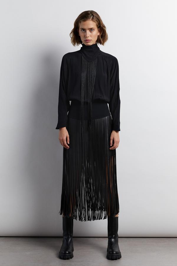 En color negro, esta blusa de manga larga con detalle de flecos en la parte delantera y cierre de lazada en la parte trasera tiene un precio de 15,99 euros.