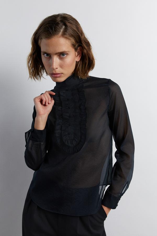 Esta camisa de organza transparente de color negro con detalle de pechera tiene también un precio rebajado de 15,99 euros.