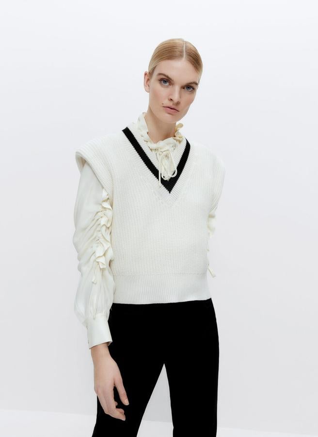 Efecto hombreras y acabados en rib para este chaleco en color crudo con escote de pico y franja a contraste en el mismo en negro. Cuesta 79 euros y podemos encontrarlo en las tallas S y M.