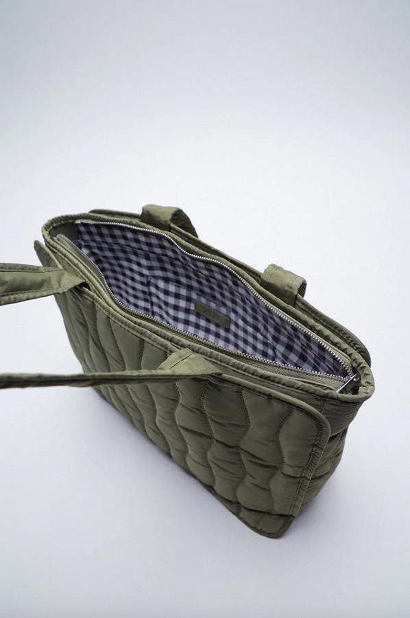 Este bolso shopper de Zara en verde caqui viene con cuerpo acolchado, asas de hombro e interior forrado con tejido de cuadro vichy. Con cierre superior de cremallera, cuesta 25,95 euros.