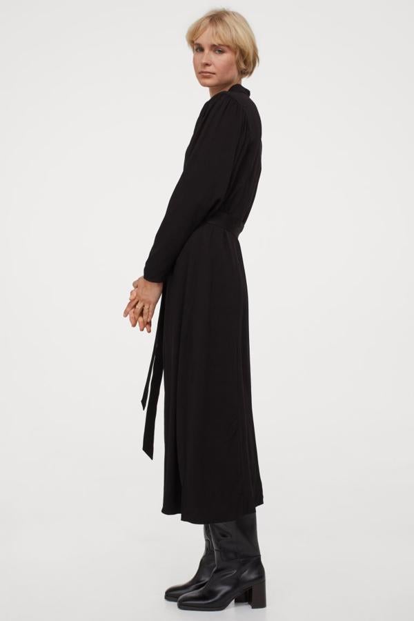 Este vestido negro confeccionado en viscosa sostenible viene con cuello elevado, cierre de botones frontal a tono, mangas jamón y cordón de anudar extraíble en la cintura también en negro. Podemos encontrarlo entre las tallas XS y XXL por 29,99 euros.