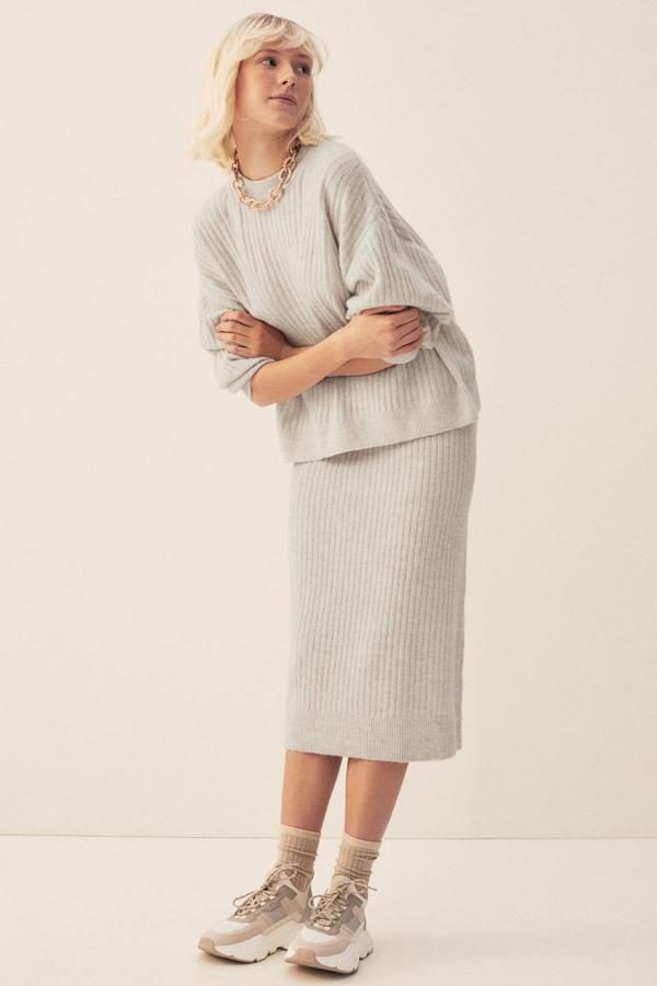 Disponible en gris claro jaspeado y beige claro jaspeado, esta falda midi de H&M en punto de canalé suave confeccionada con poliéster reciclado. Es de talle alto y tiene la cintura elástica revestida y abertura posterior. Cuesta 19,99 euros y está disponible entre las tallas XS y XXL.