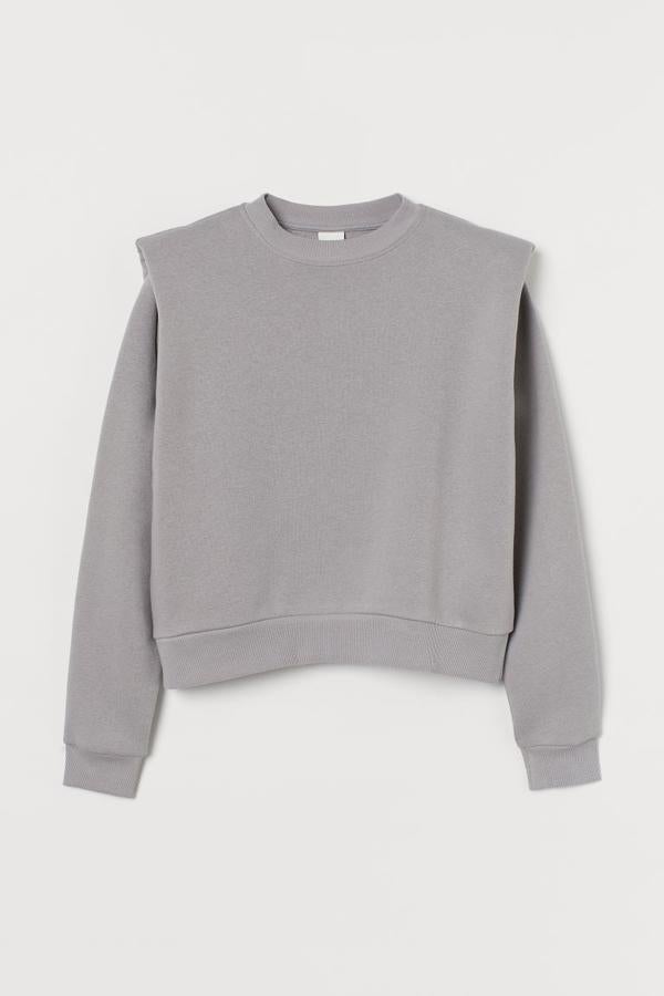 En mezcla de algodón y poliéster reciclado con cuello redondo, hombros marcados con hombreras y ribete elástico de canalé en escote, puños y bajo, esta sudadera gris de H&M tiene un precio de 14,99 euros y está disponible entre las tallas XS y XXL.