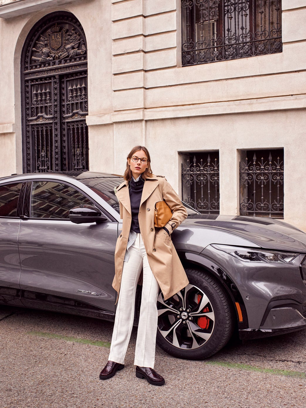 Gabardina de Boss, sudadera de Under Armour, camisa de El Corte Inglés y pantalones de Pertegaz. Gafas de Eyepetizer, bolso de Loewe y mocasines de Mango. El coche es el modelo Mustang Mach-E de Ford.