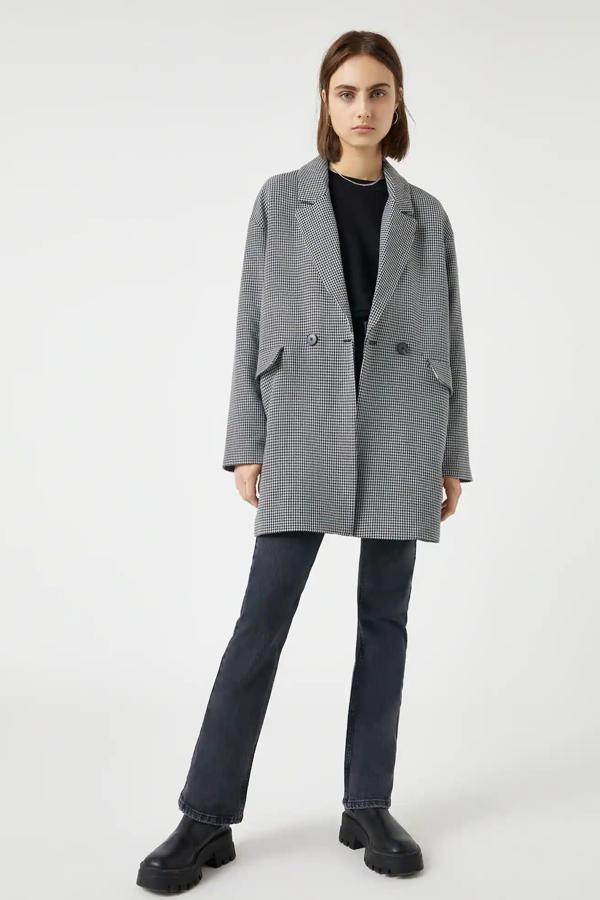 Con estampado pata de gallo, este abrigo ligero con bolsillos laterales y doble botón en la parte delantera tiene un precio rebajado de 19,99 euros.