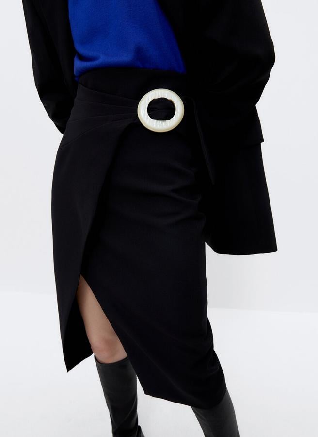 Diseño midi con abertura central cruzada para esta falda negra que viene con hebilla decorativa a contraste en un lateral ha pasado de costar 89 euros a 44,95 euros pero solo está disponible en la talla S.