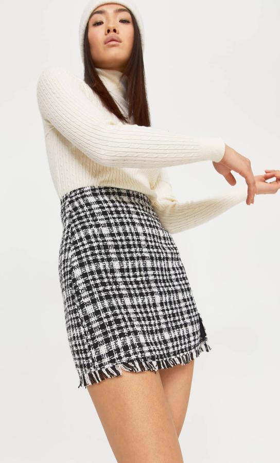 De tiro alto y diseño mini, esta falda con abertura lateral y detalle de bajo desflecado en estampado de cuadros blancos y negros podemos encontrarla entre las tallas 32 y 44 por 19,99 euros.