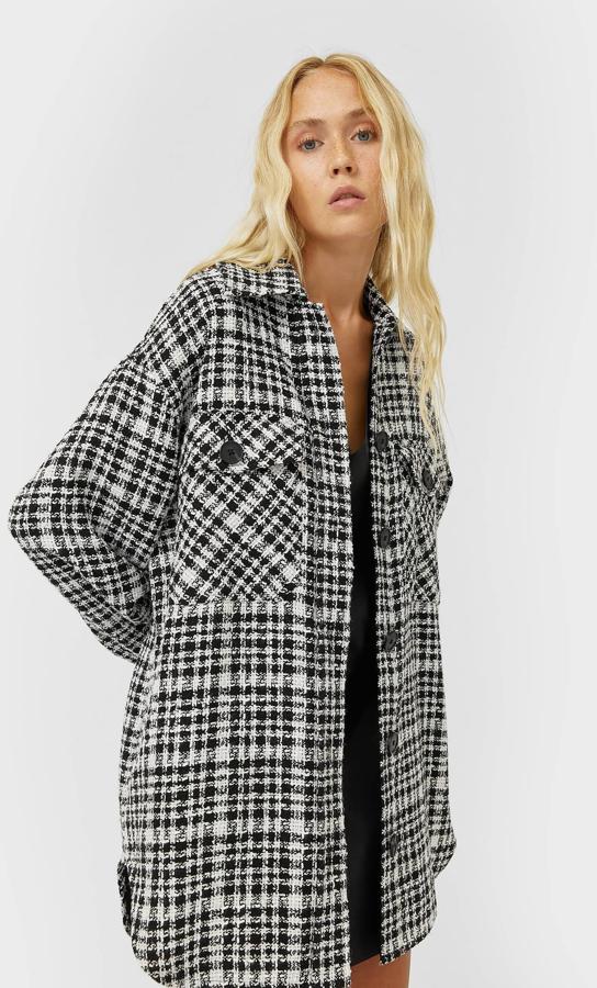 Con cuello solapa y bolsillos de plastrón con solapa y botón en el pecho, esta sobrecamisa en negro y blanco con estampado de cuadros viene con bolsillos laterales ocultos en costura, bajo redondeado asimétrico y cierre frontal de botones a contraste en negro. Cuesta 35,99 euros y está disponible entre las tallas XS y XL.