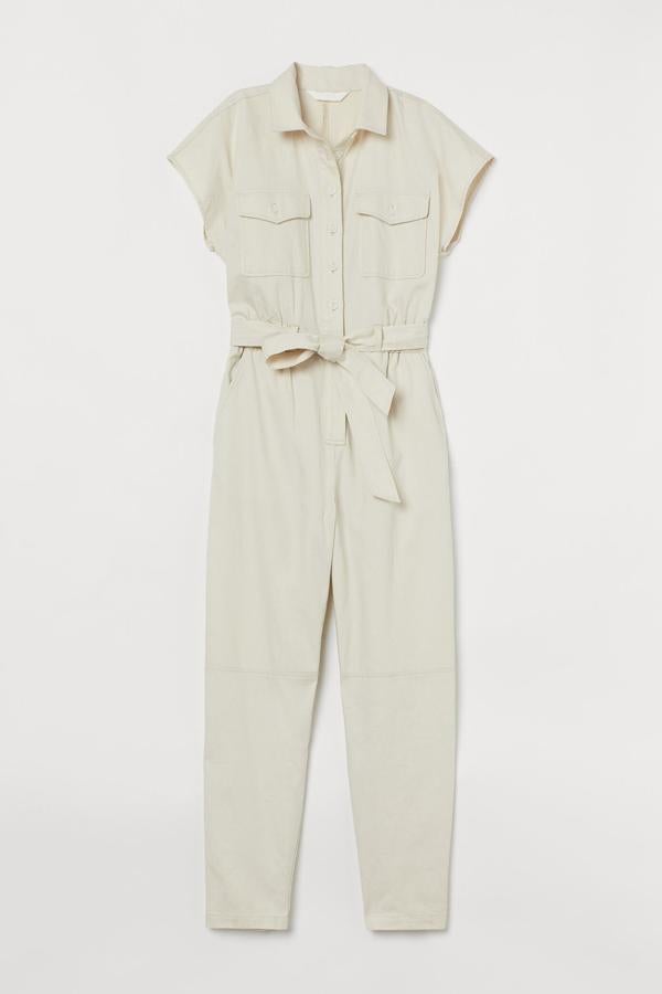 Confeccionado en suave algodón de color beige claro, este mono tobillero de manga corta con botones delanteros y cinturón tiene un precio de 39,99 euros.