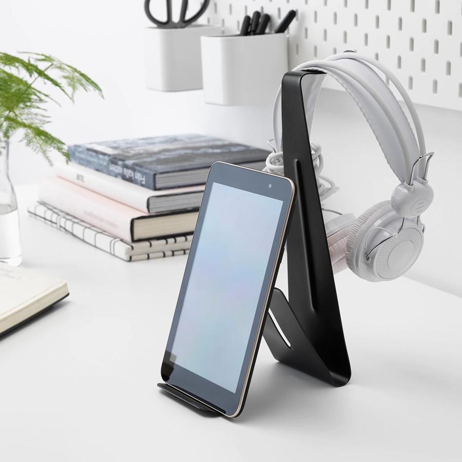 En color negro, este soporte es perfecto para teléfonos o tablets y tiene un precio de 3 euros. Cuenta con un gancho para colgar los auriculares.