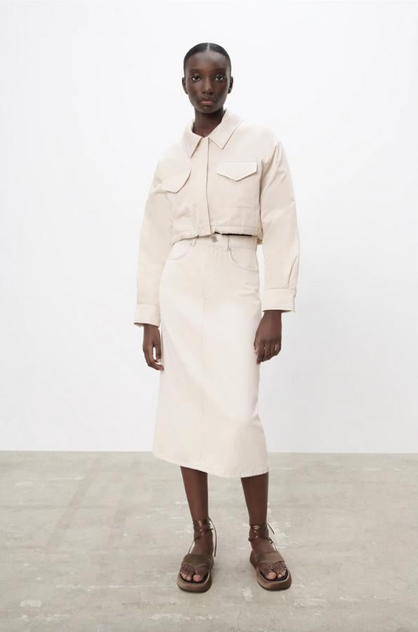 En color arena, con diseño midi de tiro alto, cinco bolsillos y bajo con abertura en espalda, esta falda de Zara está confeccionada con algodón orgánico y podemos encontrarla entre las tallas XS y XXL por 25,95 euros.