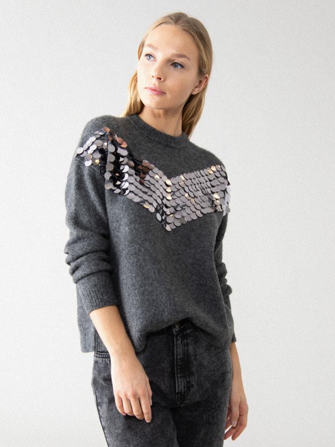 De corte holgado y confeccionado en tejido de tacto suave, este jersey en gris marengo con detalle de lentejuelas grandes en el frontal ha pasado de 19,99 euros a 9,99 euros y podemos encontrarlo entre las tallas XS y L.